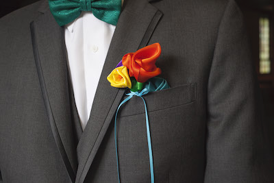 ribbon flower boutonniere attached with a pin to a suit jacket pocket