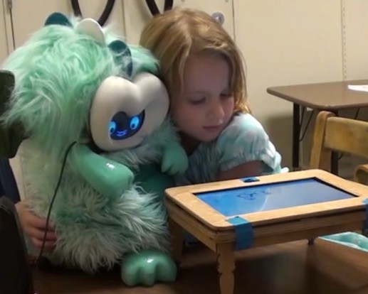 girl hugs fluffy dragon robot in front of a small play table