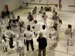 A group of fencers in white gear standing around.