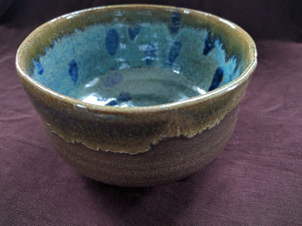 side-top view of a brown bowl with turquoise and blue polka dots inside