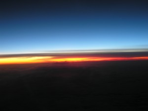 sunset from an airplane curve of the earth with dark blue above and glowing yellow-red on the horizon