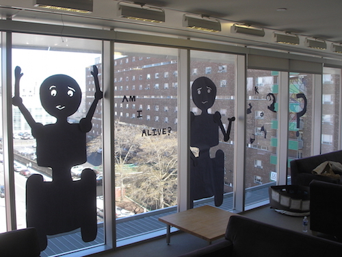 paper robots hung on windows saying 'am I alive?'