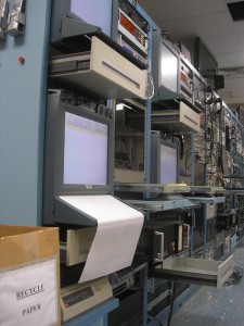 wall of old DOS computers, monitors, drawers, printers, cables