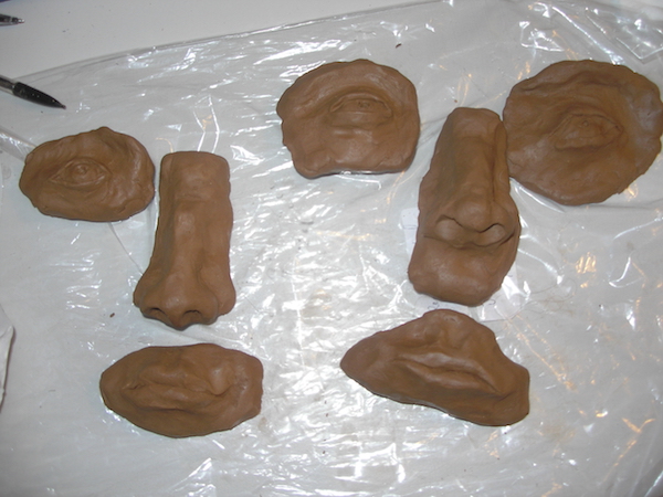fairly realistic eyes, noses, and mouths sculpted out of brown clay