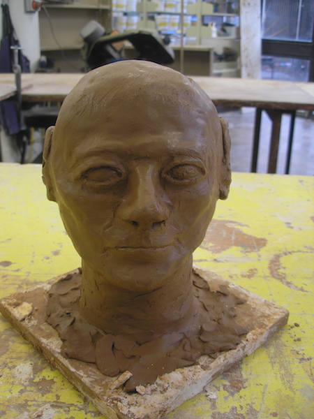 a bald head sculpted in brown clay, features a little rough around the edges