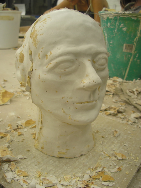 plaster head with rough patches, excess plaster from the mold stuck in the ears, mouth, and seam line