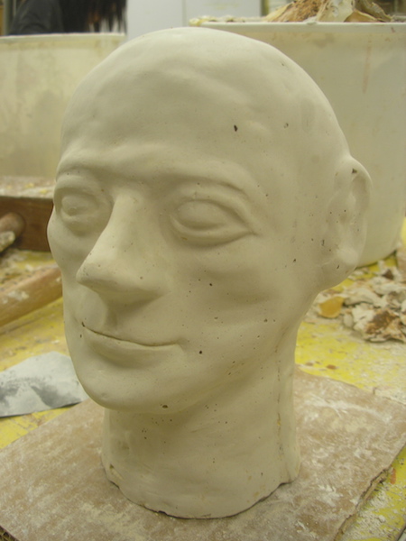 a plaster casting, smoothed, with calm, rounded features and a slight smile