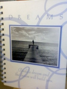 notebook spiral bound periwinkle-blue notebook, photo on the front and the words "DREAMS: Build a dream and the dream will build you"