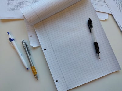 a pen sitting on a pad of paper with two extra pens beside it