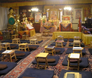 _the shrine room in the temple: five rows of cushions on the carpet leading up to altars and statues at the front of the room_