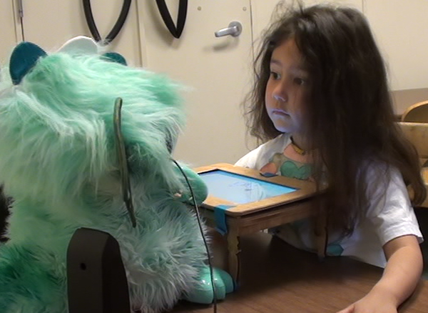Child playing with storytelling robot Girl looking intently over a mini table at a dragon robot