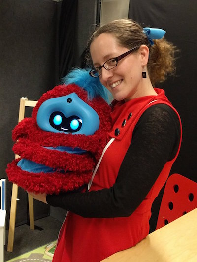 me wearing a red dress holding tega, a fluffy red and blue robot