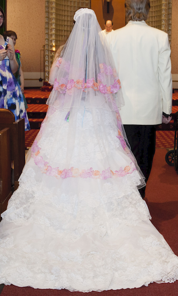 back of a woman wearing a white wedding dress with a veil draped down her back